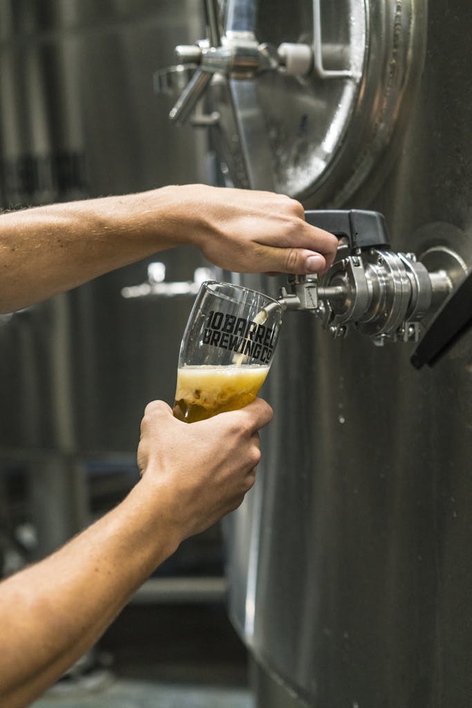 Person Filling Up Beer Glass from Tap Machine